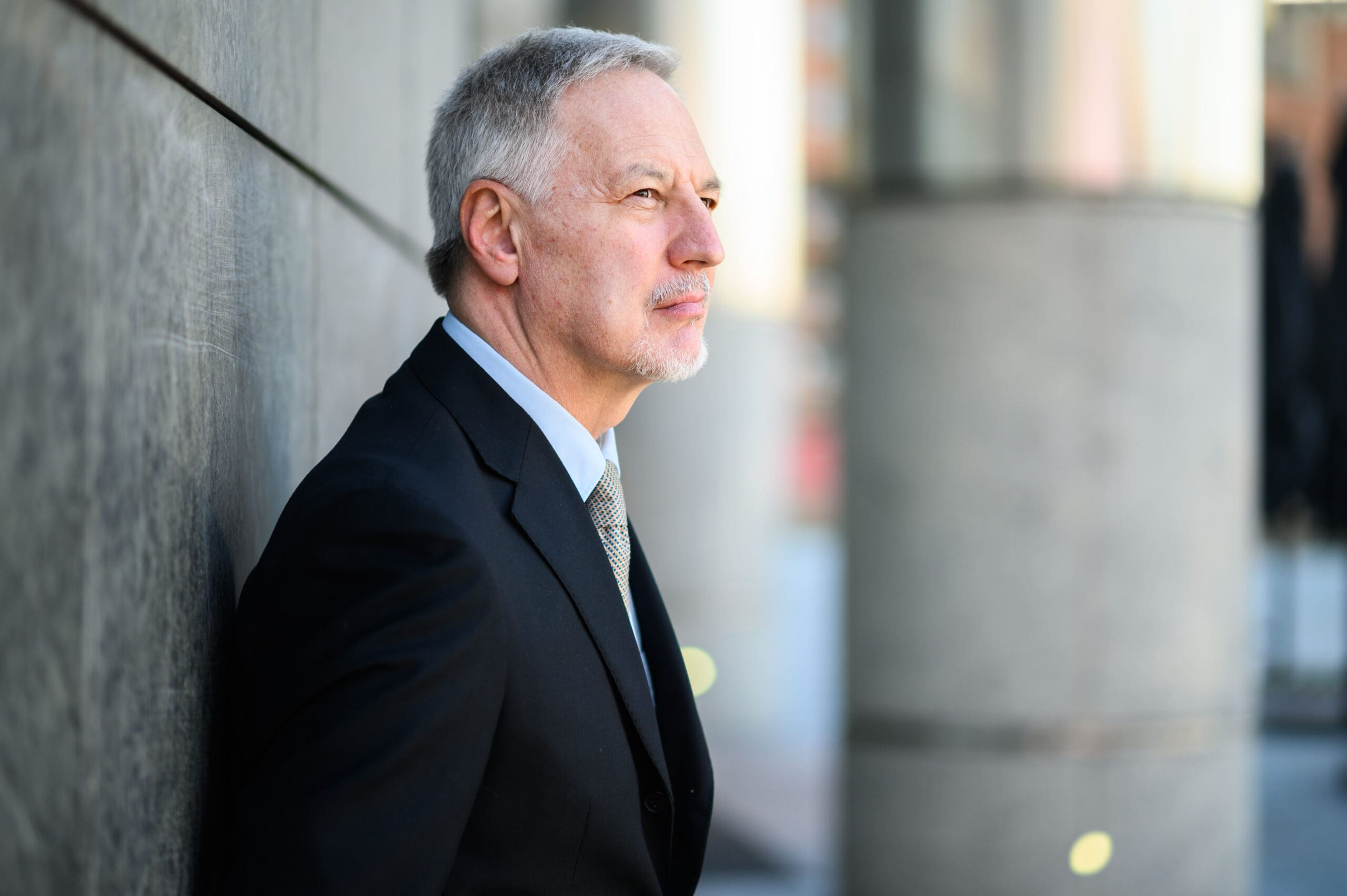 profile photo of man in suit leaning against a wall