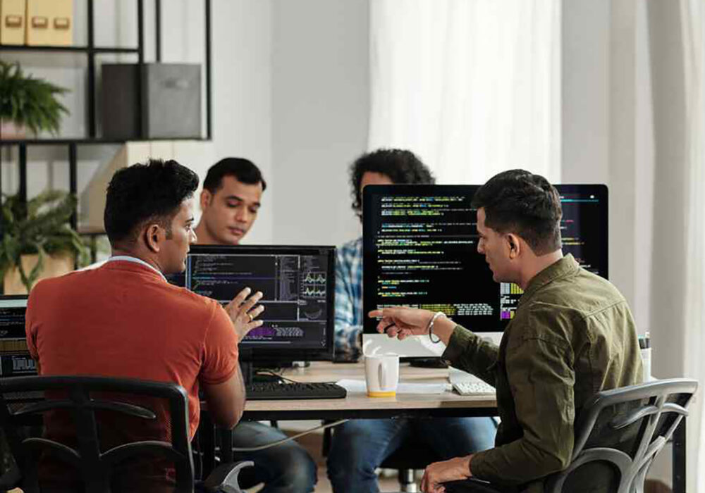 photo of four people working and talking at a desk