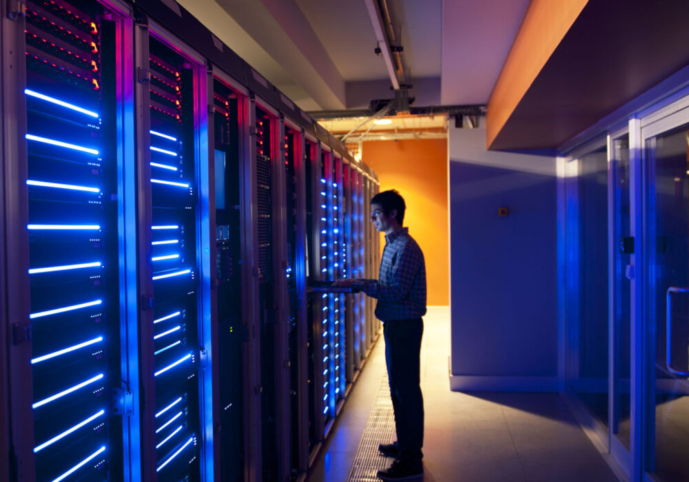 photo of man working at large server wall