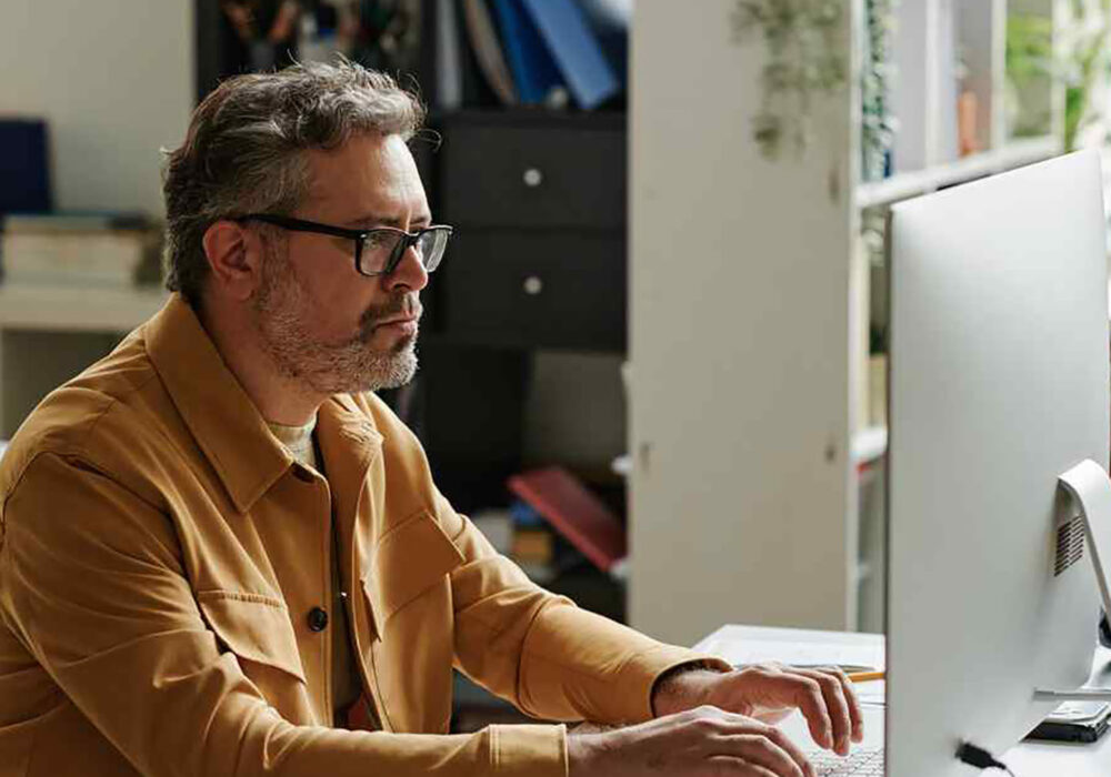 photo of man working at imac desktop computer