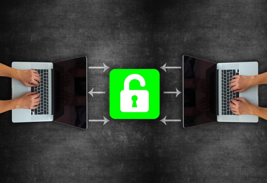 one macbook on each side with a person's hands typing at each, with a green padlock icon in the center