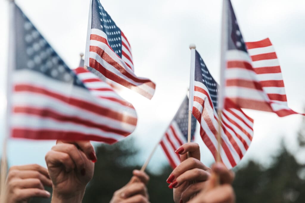 cluster of hands holding small American flags